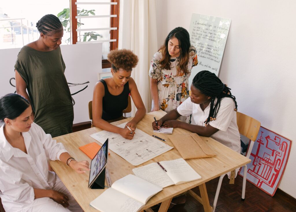 people/women of color gathering around a table working
