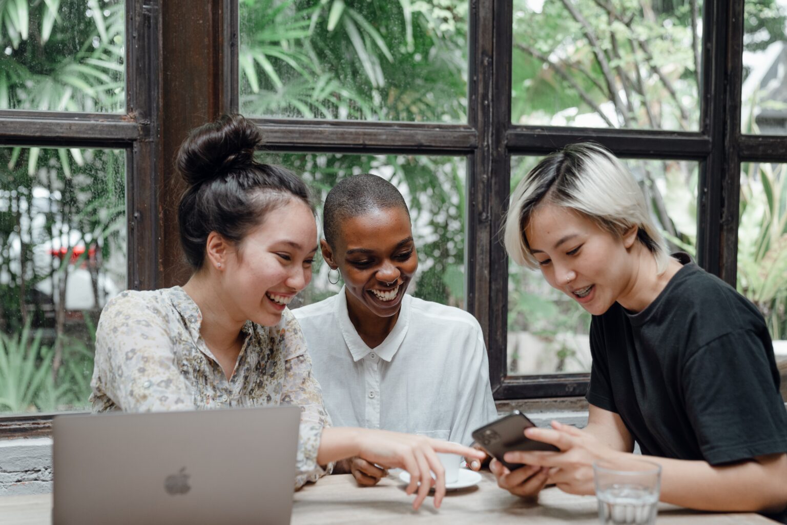 three PoC/WoC gathering around a laptop smiling